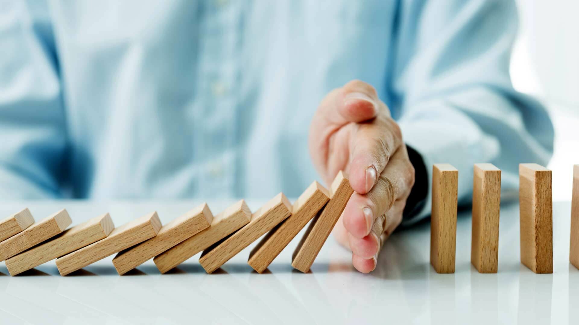 Energielieferung Hand hält umfallenden Dominosteine auf