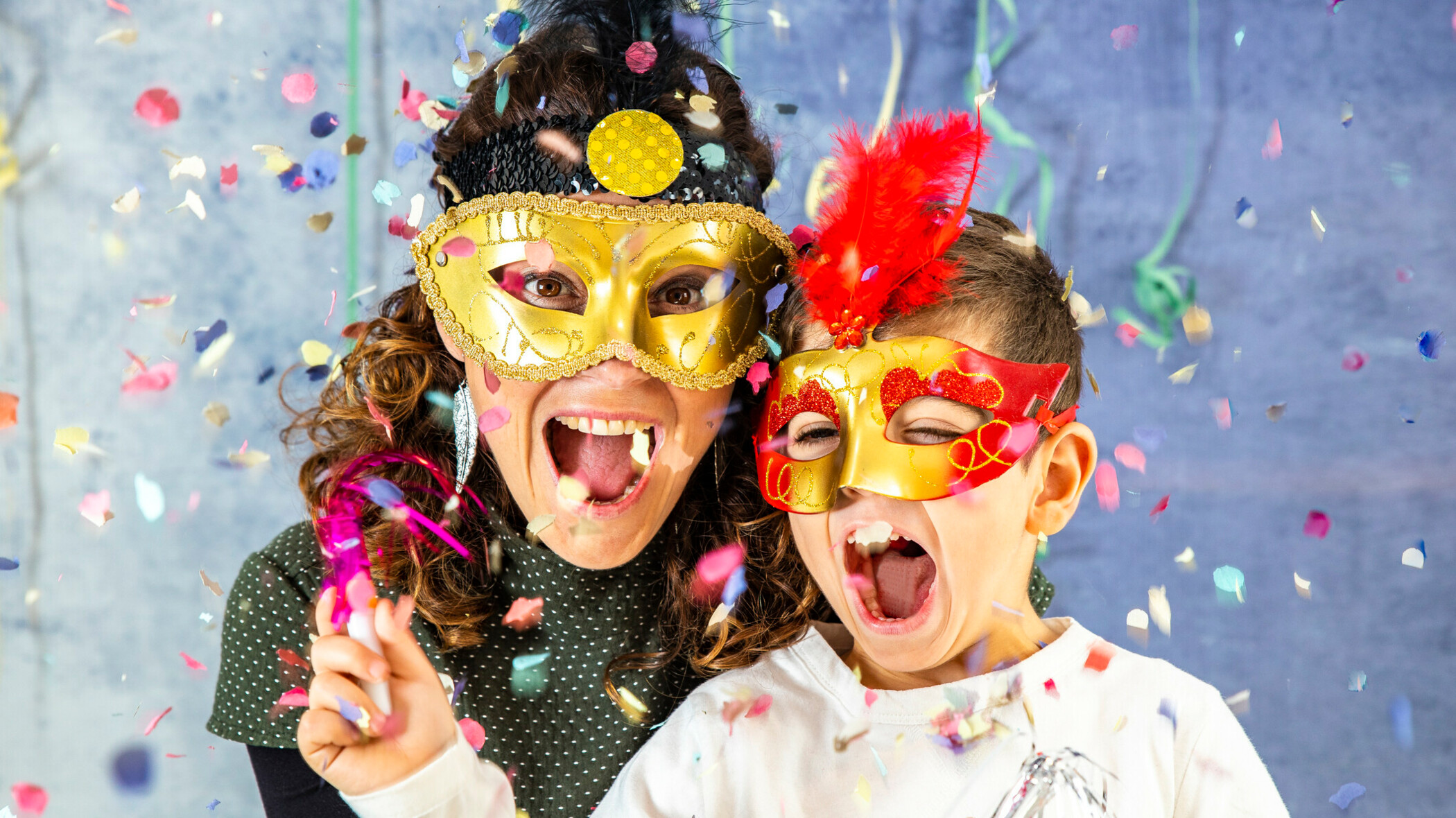 Karneval Konfetti Mutter und Kind verkleidet hinter Konfetti.