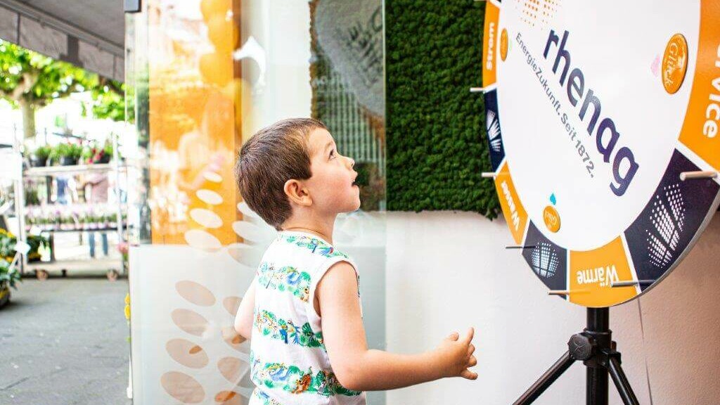 Nachhaltigkeit 2023 Kleiner Junge dreht an einem Gewinnspielrad.