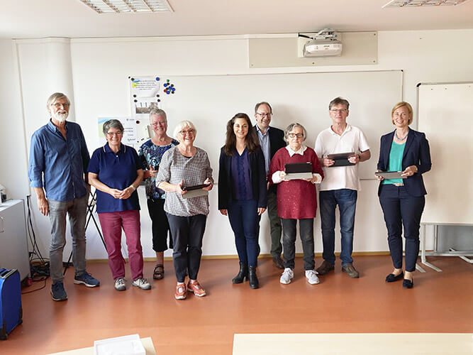 Tablets 01 Eine Menschengruppe in einem Raum mit Tablets in den Händen.