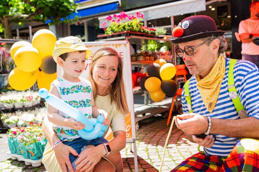 Nachhaltigkeit Clown mit Frau und Kind erstellt Luftballon-Figuren