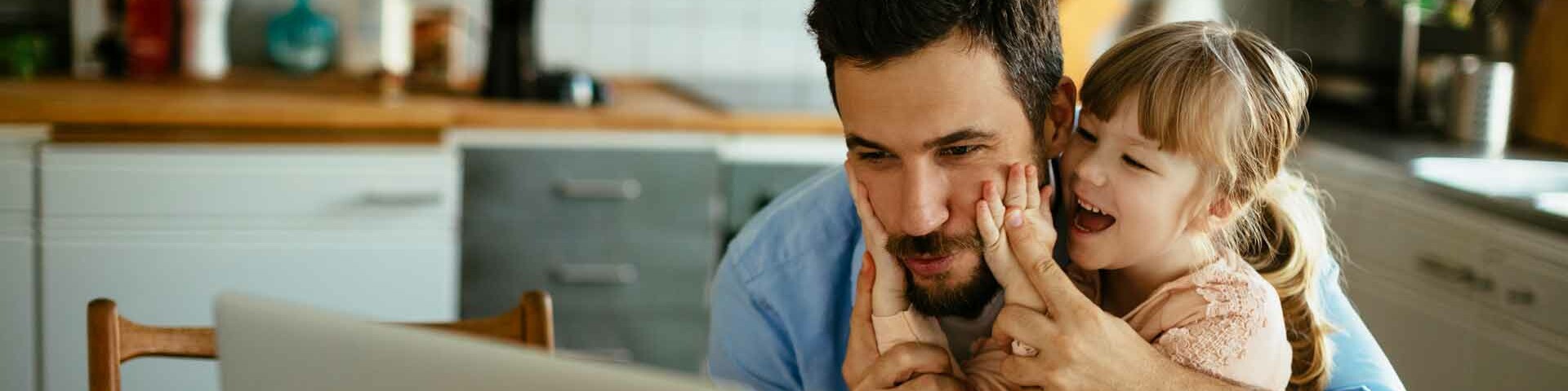 Stromsparen Vater und Tochter sitzen am Tisch vor einem Laptop