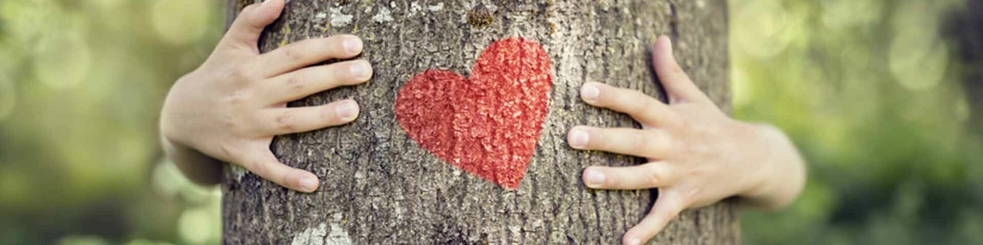 Motor Kind umarmt Baum mit Herz auf dem Stamm