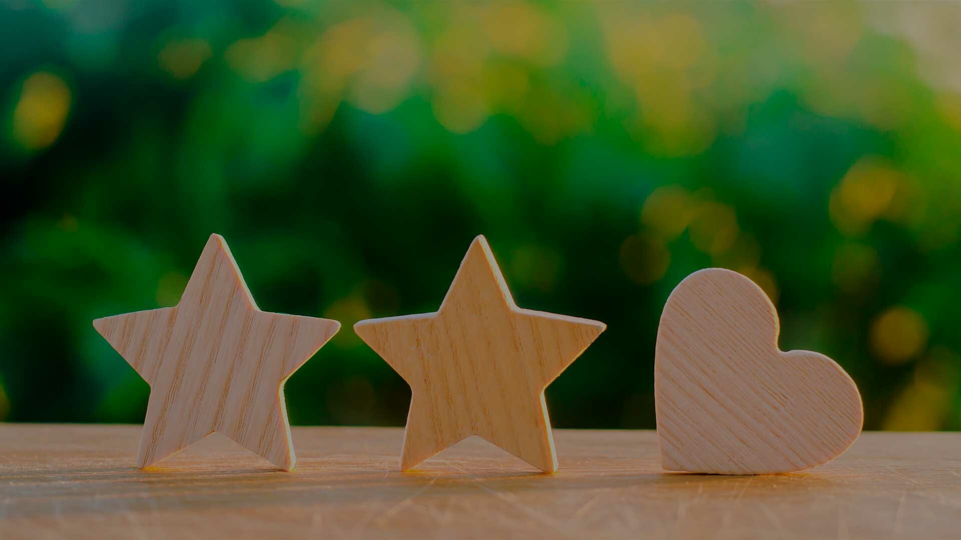 Mehrfach ausgezeichnet Holzsterne und Herz vor grünem Hintergrund