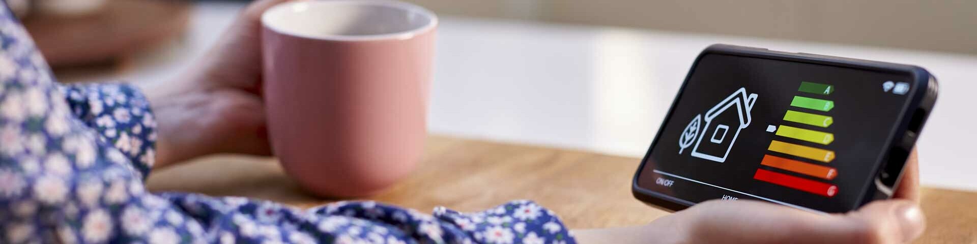 Energiesparen Energieeffizienzbild auf einem Mobiltelefon, Hand mit Kaffeetasse
