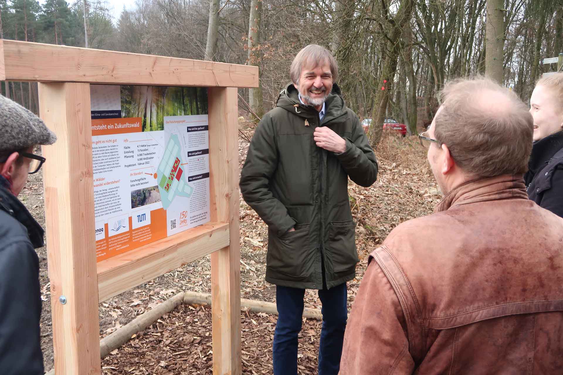 Zukunftswald 05 Projektmitarbeiter stehen vor einer Erklärtafel und lachen.