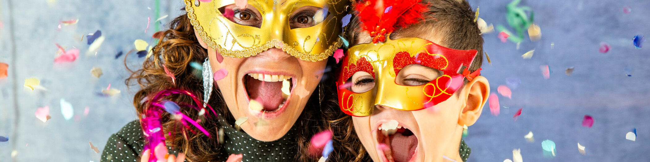 Karneval Konfetti Mutter und Kind verkleidet hinter Konfetti.