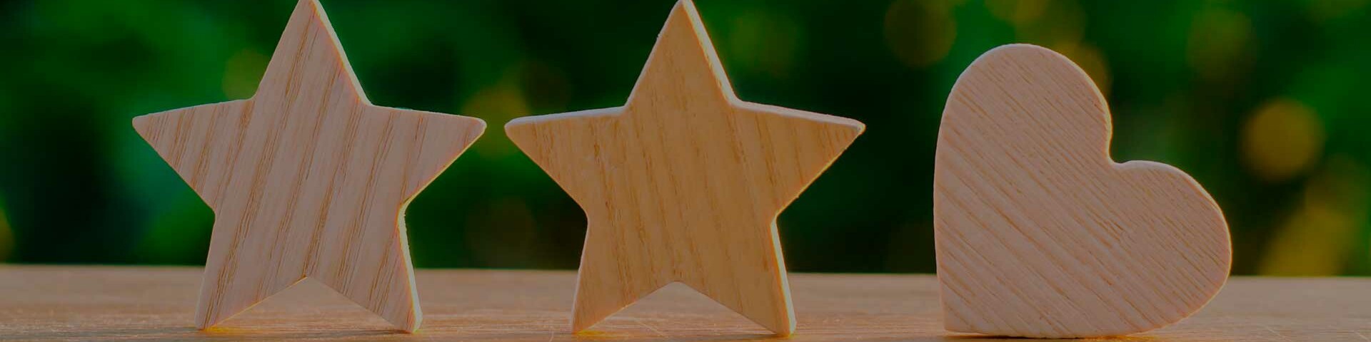Mehrfach ausgezeichnet Holzsterne und Herz vor grünem Hintergrund
