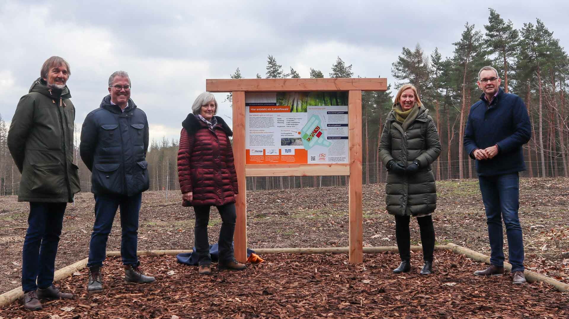 Zukunftswald Projektmitglieder stehen neben der Erklärtafel für den Zukunftswald.