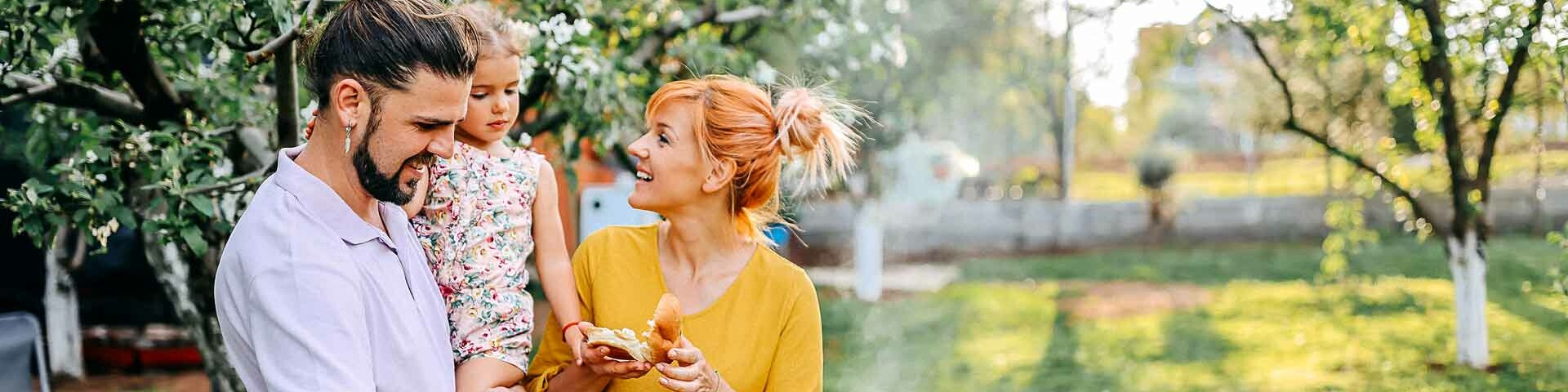 Grillen Junge Familie vor einem Grill im Garten